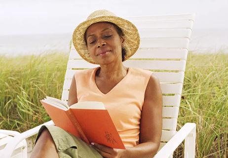 Person reading at beach wearing sunhat