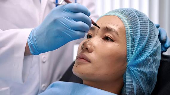 Doctor making marks on female patient's face