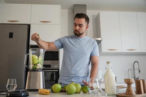 Person adding fruit to blender to make a smoothie