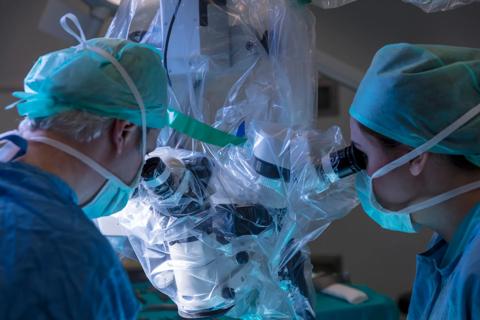 Surgeons looking through microscope during microsurgery