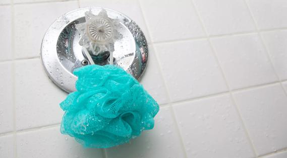 Wet plastic loofah hanging on shower knob