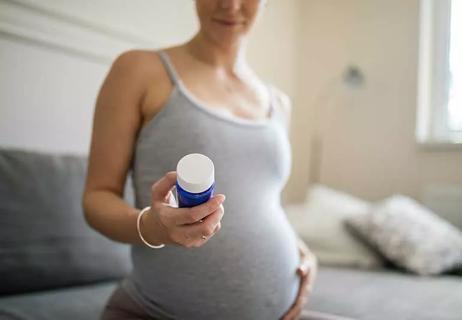 pregnant woman holding pill container