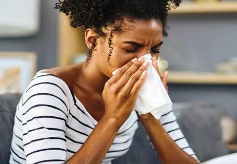 Person sneezing and wheezing inside home.