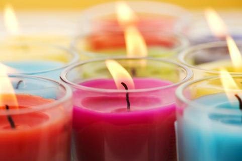 Assorted colorful lit candles in glass votives