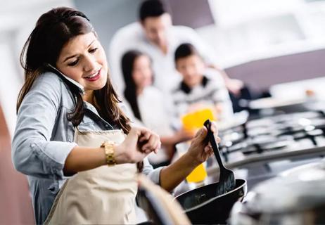 Stressed out mom cooking looking at her watch with family in background