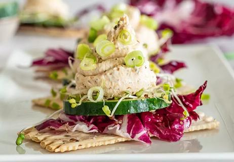 Salmon mouse on a cracker with red cabbage, cucumber, sprouts, and green onions