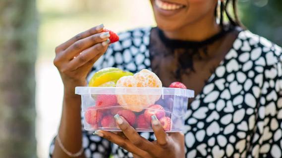 Person enjoying container of assorted fruit