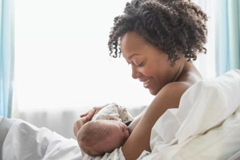 Woman breast feeding baby in cradle hold position.