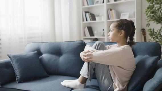 Young girl sitting on couch looking off into the distance