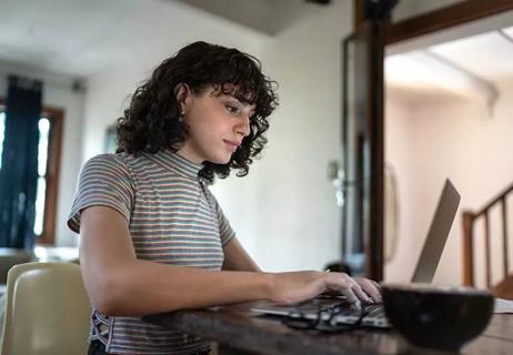 trans woman at home researching on laptop