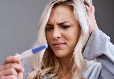 Woman is surprised and confused by positive pregnancy test