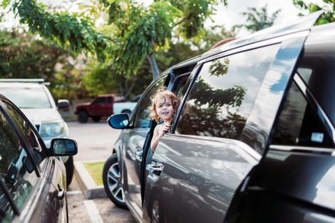 Happy toddler standing in, looking out van door