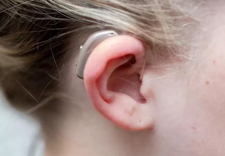 Closeup of person wearing thier BiCros hearing aid in their right ear.