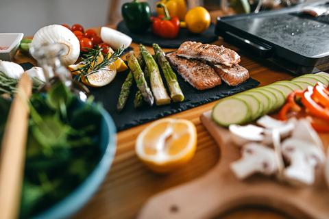 Table filled with fresh veggies and grilled asparagus and salmon