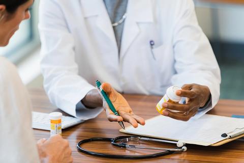 Healthcare provider, with bottles of prescription medication, discussing them with a patient in office