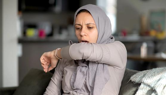 Person coughing into the crook of their elbow