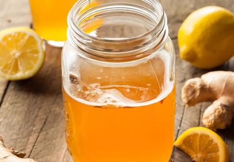 Close-up shot of kombucha in a mason jar with lemon and ginger.