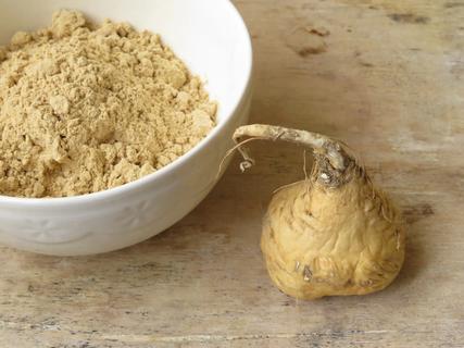 A maca root next to a bowl of maca powder