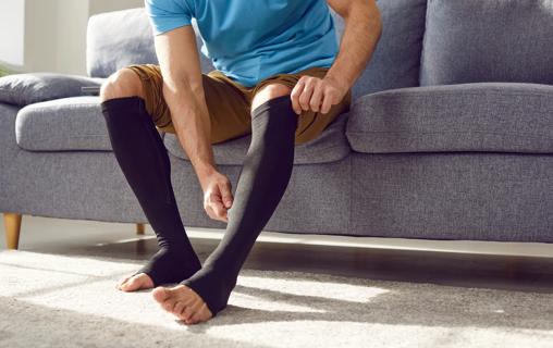 Person sitting on couch, adjusting their compression socks