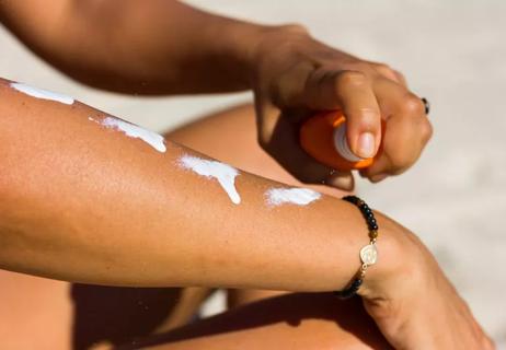 person on beach applying sunscreen