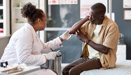 Healthcare provider examining plaques on patient's elbow