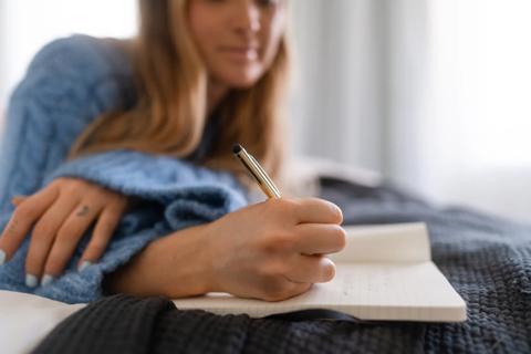 Person lying in bed journaling