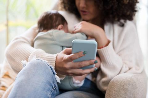mom holds phone for telehealth appointment