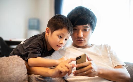 Caregiver showing child how to use a cell phone
