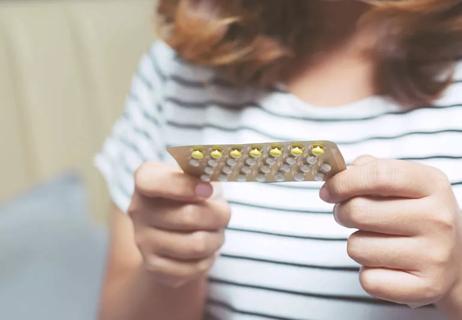 Woman hands opening birth control pills