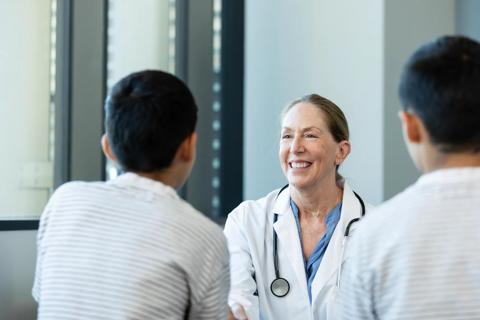 Smiling healthcare provider talking to two young teen brothers