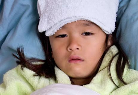 Child with fever has wet washcloth on forehead.