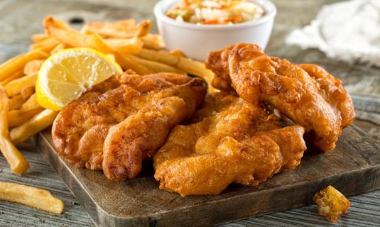 Wooden tray filled with fried fish, french fries and coleslaw