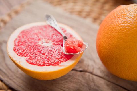 Halved grapfruit with spoon, and whole grapefruit