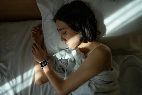 Person asleep in bed wearing a smartwatch, tracking their sleep