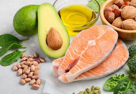 various low-cholesterol foods on a table including avocado, beans, oil, nuts and fish