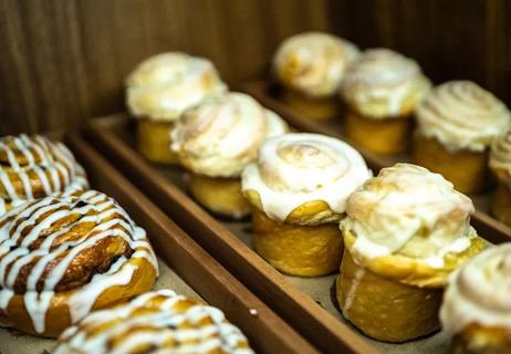 Muffins and sweetbreads with frosting on trays at bakery.