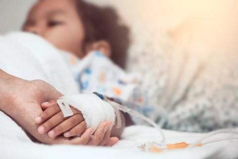 Caregiver holding sick child's hand