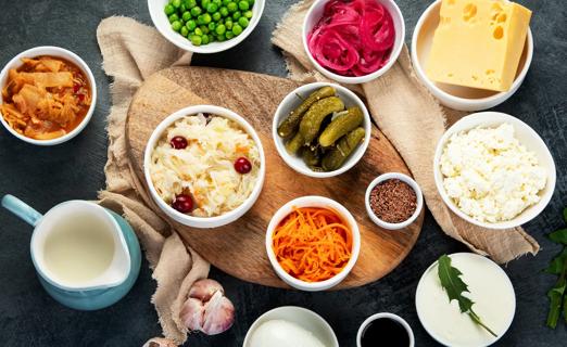A variety of probiotic foods, like pickles, cheese and sauerkraut, are laid out on a table