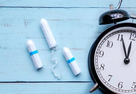 Tampons on a wooden panel next to an alarm clock.