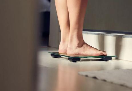Woman stepping on scale in bathroom