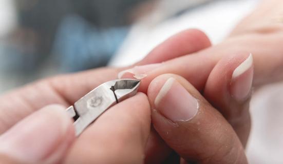Hand holding fingernail clipper, clipping nails and hangnails