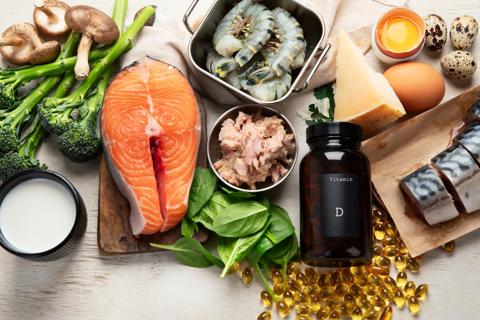 Assorted foods high in vitamin D, like salmon, with a vitamin D supplements