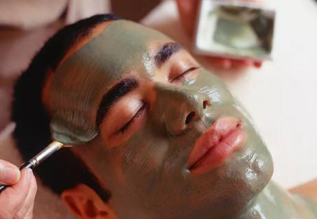 Person getting a facial mask applied by a spa professional.