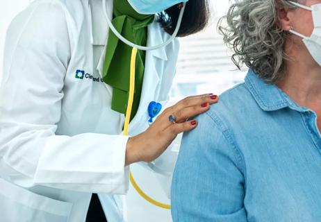 Physician or doctor listening to lungs of patient in office setting.