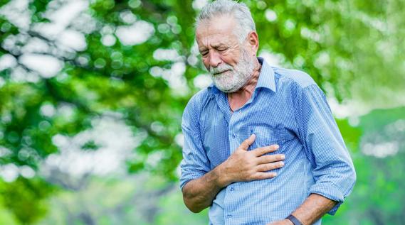 Older man walking outside, grimacing, clutching their chest