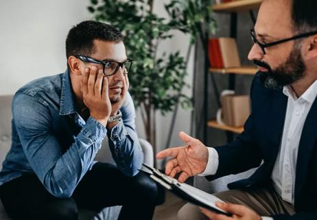 Young man during office visit with his psychiatrist discussing care