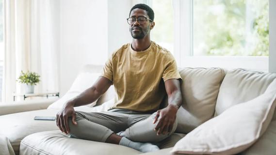 young man meditating on a sofa