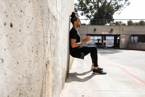 Person doing wall sits, or wall squats, outside