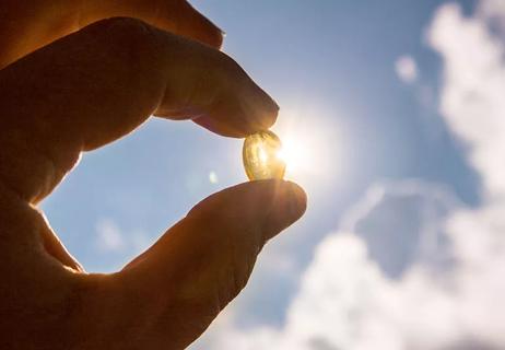 A person holding a pill up to the sun
