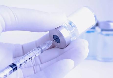 Gloved hand of nurse preparing botox injection on a white background.